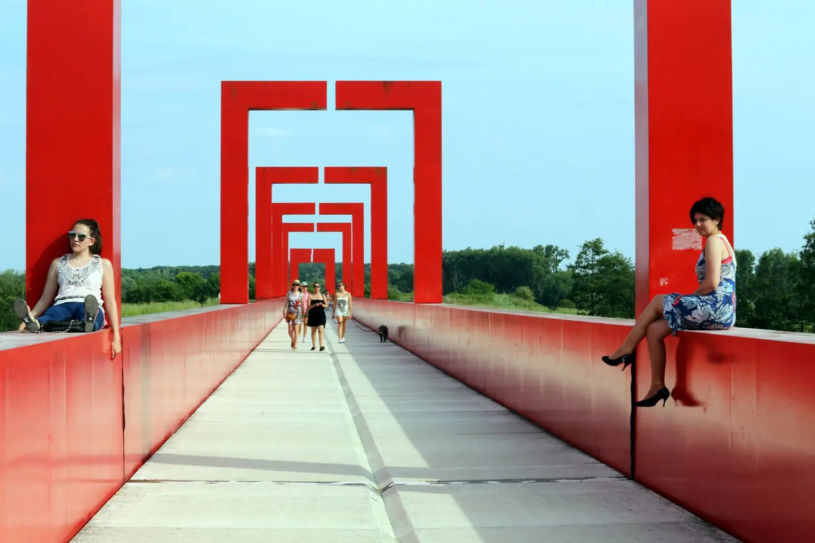 Passerelle rouge de l'Axe majeur à Cergy, avec des promeneurs en été